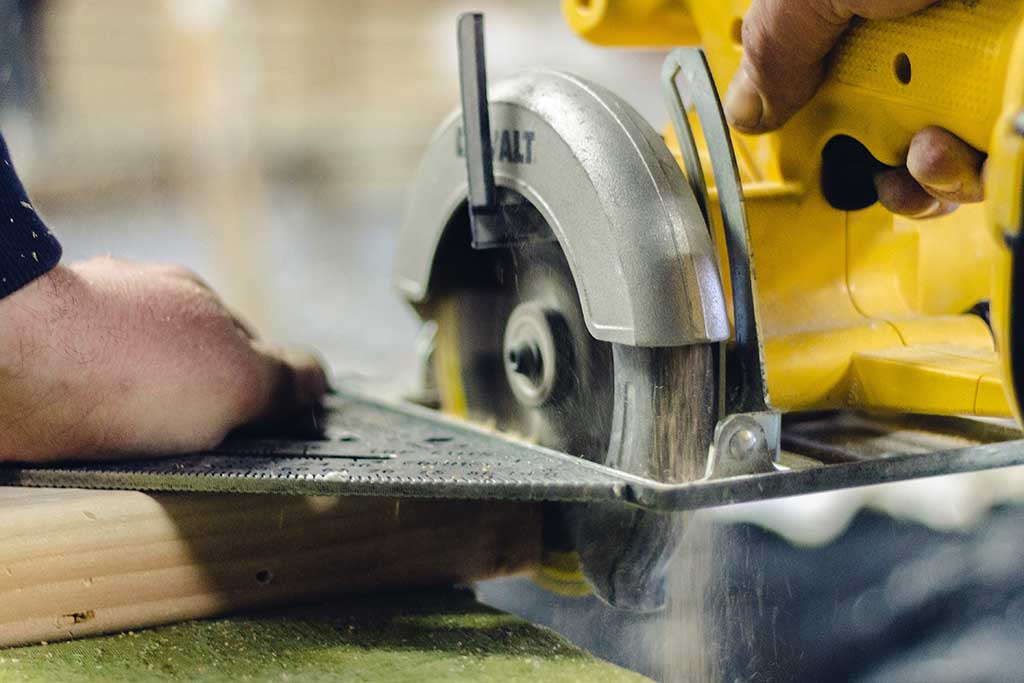 Upclose image of a handyman cutting wood with a rotary saw
