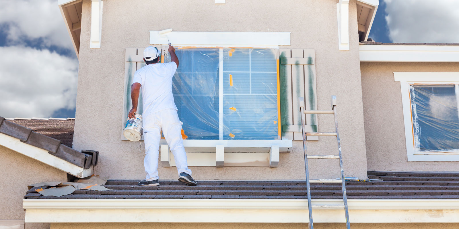 Image of a handyman painting a home's exterior