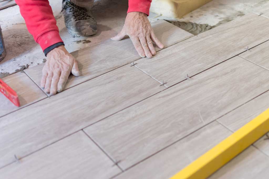 Image of a San Antonio handyman installing kitchen flooring in a kitchen remodel