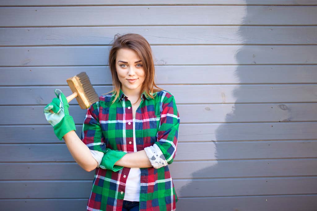Image of a handy woman painting the exterior of a home