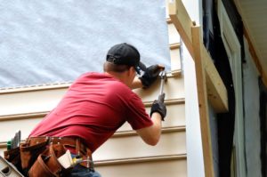 Image of a handyman repairing or replacing siding on a house
