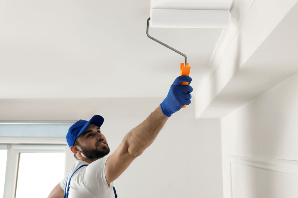 Image of a handyman painting a ceiling with a roller