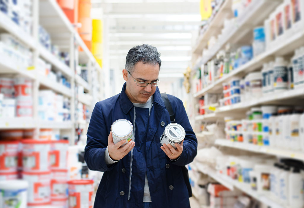 Image of a consumer reading paint can labels at a hardware store