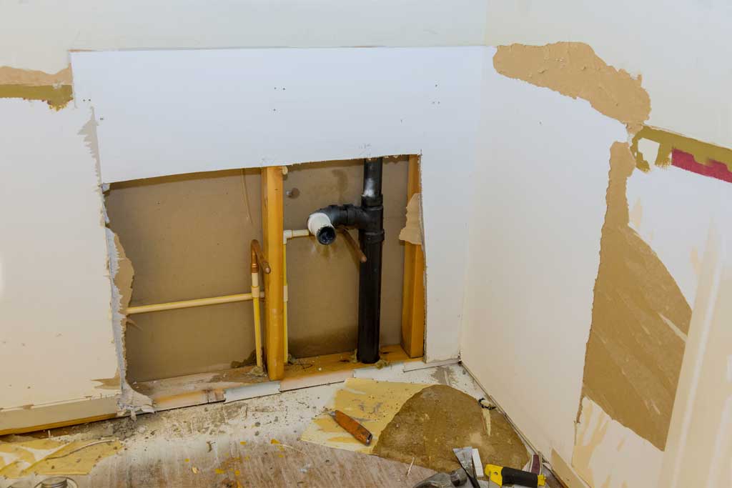 Image of a portion of drywall removed to access plumbing behind wall