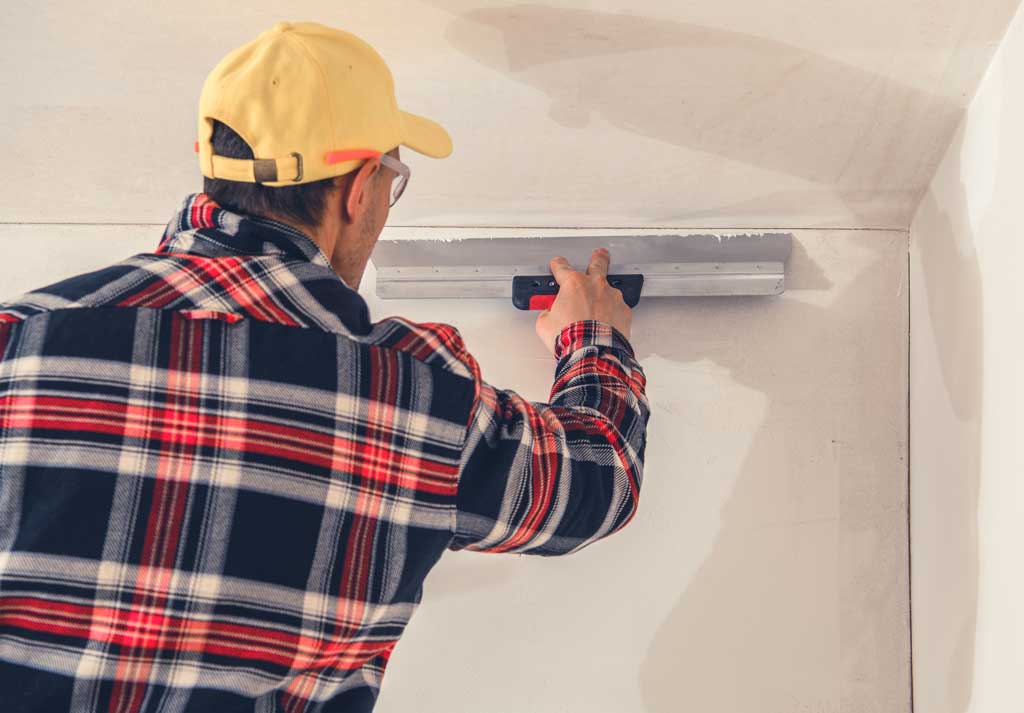 Image of a handyman repairing and patching up drywall